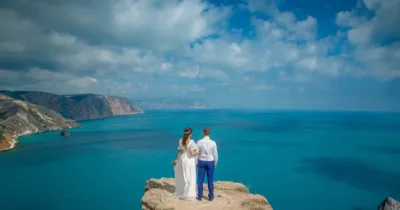 Ζευγάρι σε βράχο με θέα γαλάζια θάλασσα